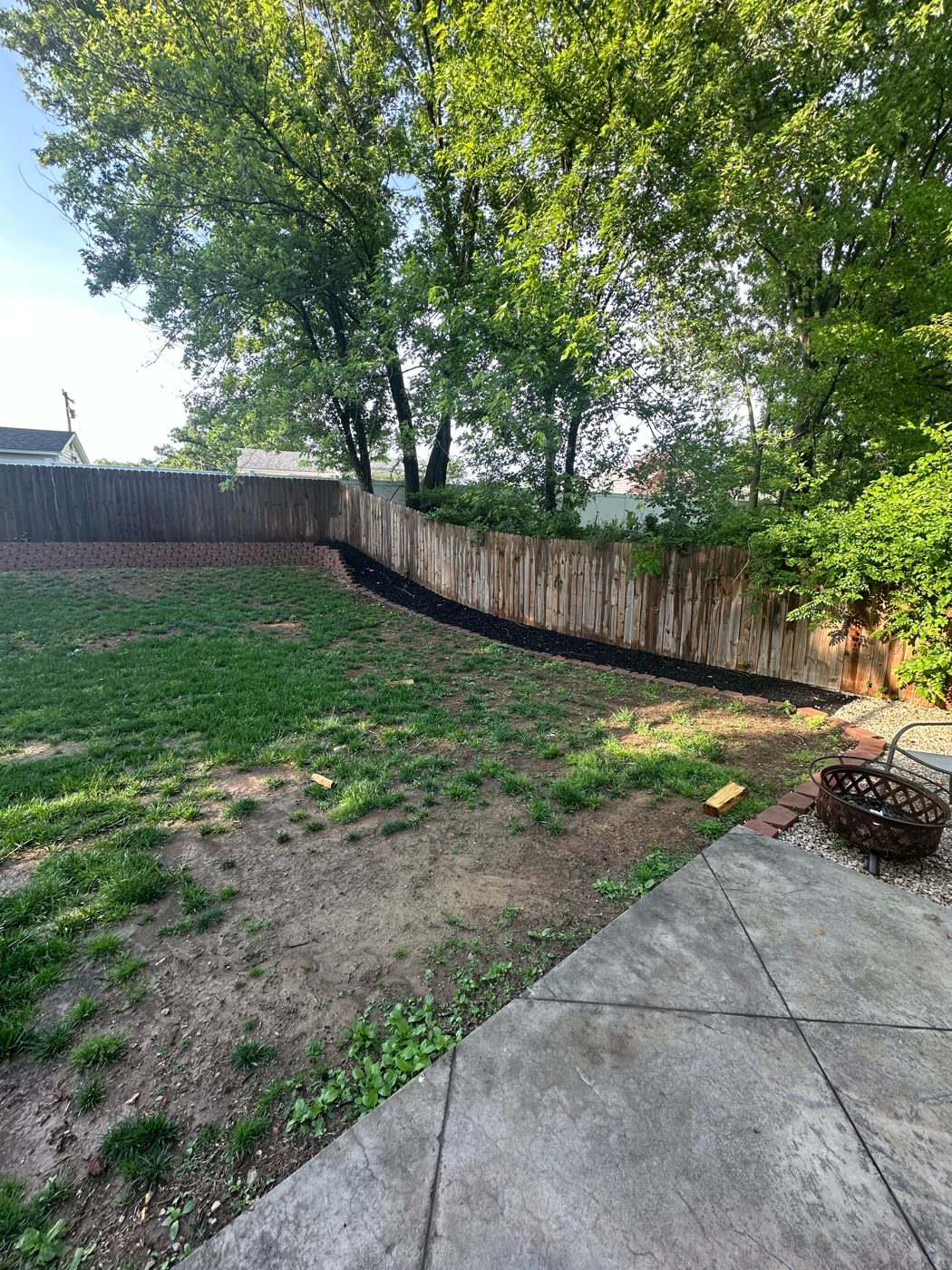 Backyard before the fire pit build: bare patchy grass by the patio